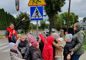 Dzieci pokazują znaki drogowe.