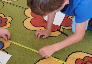 Chłopiec sprawdza długość sznurka.