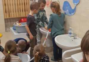 Dzieci pomagają sobie podczas wlewania wody do miski