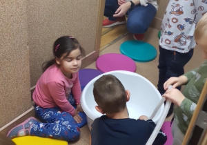 Dzieci obserwują wypływającą z węża wodę.