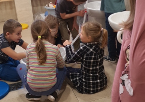 Dzieci współpracują podczas nalewania wody do miski.