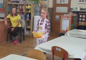 Dziewczynka niesie startą marchewkę.