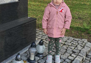 Dziewczynka stoi pod pomnikiem.