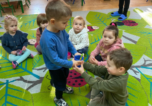 Chłopiec rozdaje kubki i szczoteczki do mycia zębów.