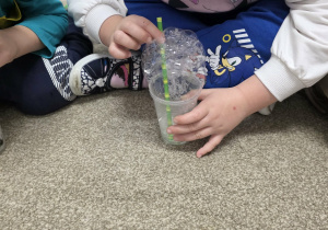 Dzieci puszczają bańki przez słomkę.