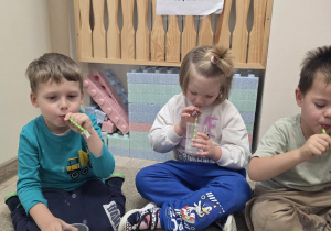 Dzieci puszczają bańki przez słomkę.