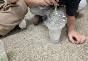 Dzieci puszczają bańki przez słomkę.