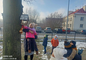 Dzieci wsypują ziarenka do karmników