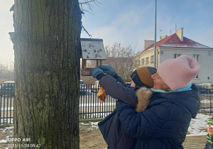 Dzieci wsypują ziarenka do karmników