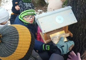 Dzieci wsypują ziarenka do karmników