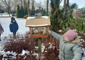 Dzieci wsypują ziarenka do karmników