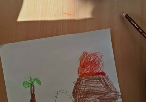 Wybuchający wulkan i dinozaur.