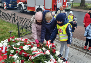 dzieci składają kwiaty pod pomnikiem Józefa Piłsudskiego