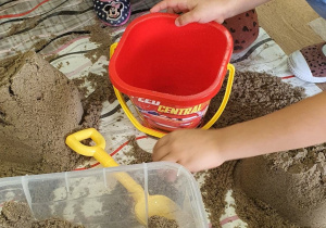 Dzieci robią babki z piasku.